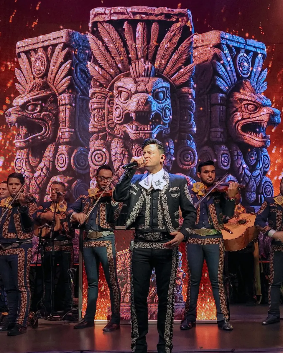 Mariachi La Chula en escenario con visual de cabezas aztecas de piedra generado con IA